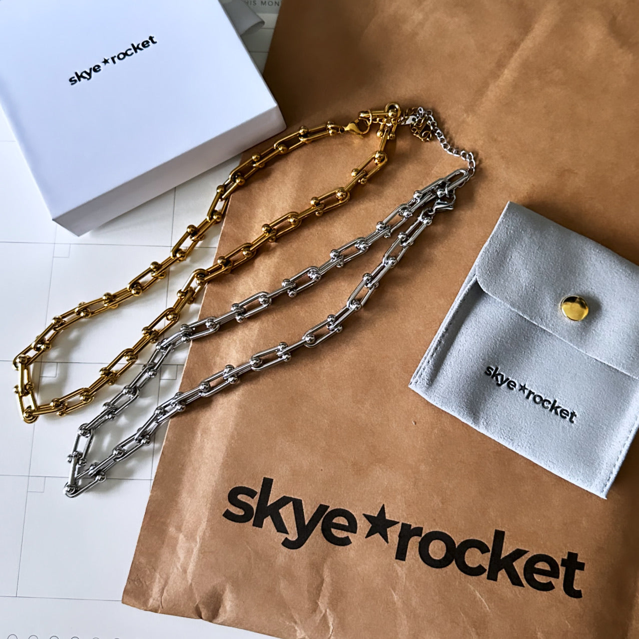 Skye and Rocket gold and silver horseshoe chain necklaces on a brown paper bag with 'skye and rocket' branding.
